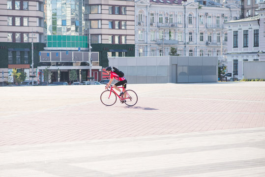 Cyclist in sportswear and a helmet rides in the city on the background of architecture. Athlete cyclist rides a bicycle in the city.