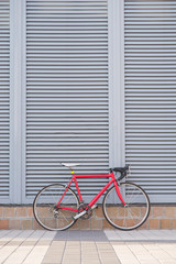 Fototapeta na wymiar Red road bike stands on the background of a gray wall. Road bike with pierced rear wheel. Sport concept. Copyspace