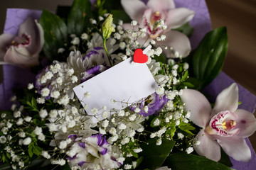 Obraz na płótnie Canvas blank white greeting card with white flowers bouquet and small red heart .top view. mock up.Stylish branding mockup to display your artworks.orchids and lisianthuses. Special day, event, invatation.