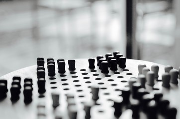 a round  wooden set of Chinese checkers in daylight with a blurred window in the background - black and white photo