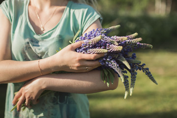 girl is standing in the field with a bouquet of lupines