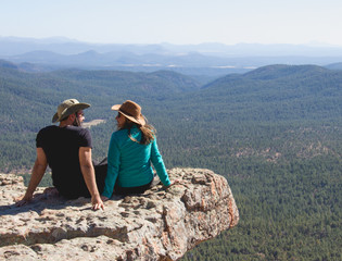 traveler young couple sitting at the edge looking and smiling each other