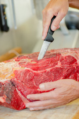 Butcher wearing a meat glove whilst preparing cut of beef