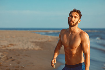 Handsome young man having fun on the beach by the sea