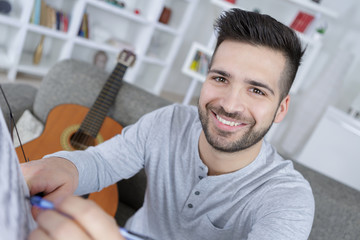 happy young man composing music with a guitar