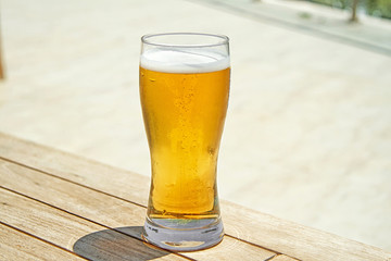 Beer in glass on wooden table. Cold beer on desk.