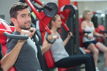Fototapeta premium young man in the and exercising shoulders with machine