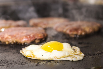 Egg that is grilled with meat cutlets, pieces to create a morning burger