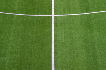 Obraz premium Photo of a green synthetic grass sports field with white line shot from above.