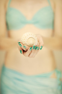 Beautiful woman hands with perfect nail polish holding little sea shell, summerly beach mood, can be used as background