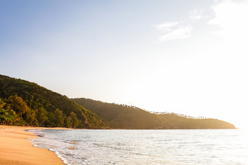 View of tropical sandy beach with small waves during a sunny day, Mae Haad beach, Koh Phangan, Thailand
