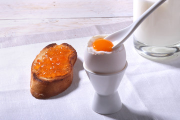Morning Breakfast set with egg, orange jam on bread toast and milk in glass.