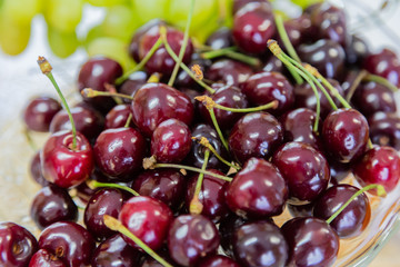 Close up of pile of ripe cherries with stalks and leaves. Large collection of fresh red cherries. Ripe cherries background