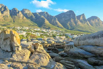 Fotobehang Grote rotsen in Camps Bay met Table Mountain National Park achter hem. Camps Bay is een van de meest exclusieve badplaatsen van Zuid-Afrika, ook wel bekend als de Rivièra van Kaapstad. © bennymarty