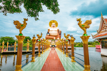 Wat Plai Laem Buddhism Temple statues during a bright sunny day with lake in the foreground in Koh...