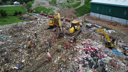 Drone shot of people and machines at massive garbage dump in Jakarta, Indonesia - Powered by Adobe
