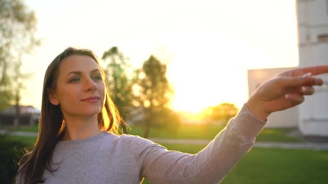 Woman launches paper airplane against sunset background. Slow motion