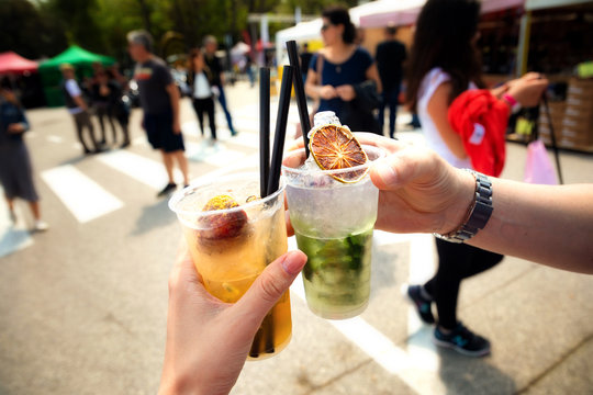 Hands holding a glass of mojito on city street, people on nackground