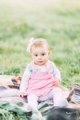Cute little girl sitting on the grass on a sunny summer day