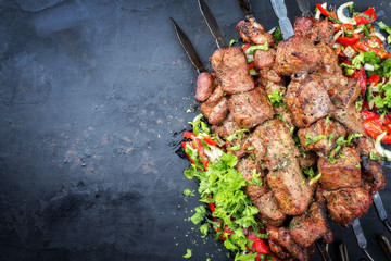 Traditional Russian shashlik on a barbecue skewer with vegetable and onion as top view on an old board with copy space left