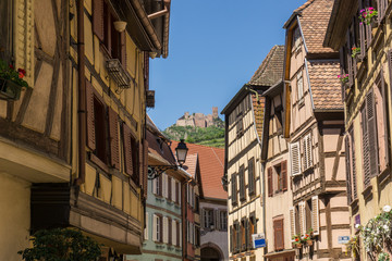 Fototapeta na wymiar Steet in Beauville village with ruins up the hill, Alsace, France