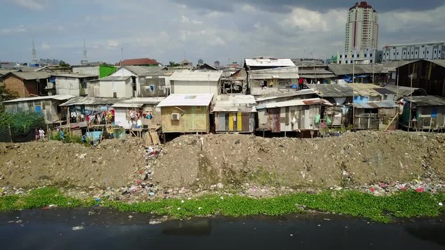 Kids throw rocks at a drone flying past slum housing and pollution, poverty in suburbs of Jakarta, Indonesia