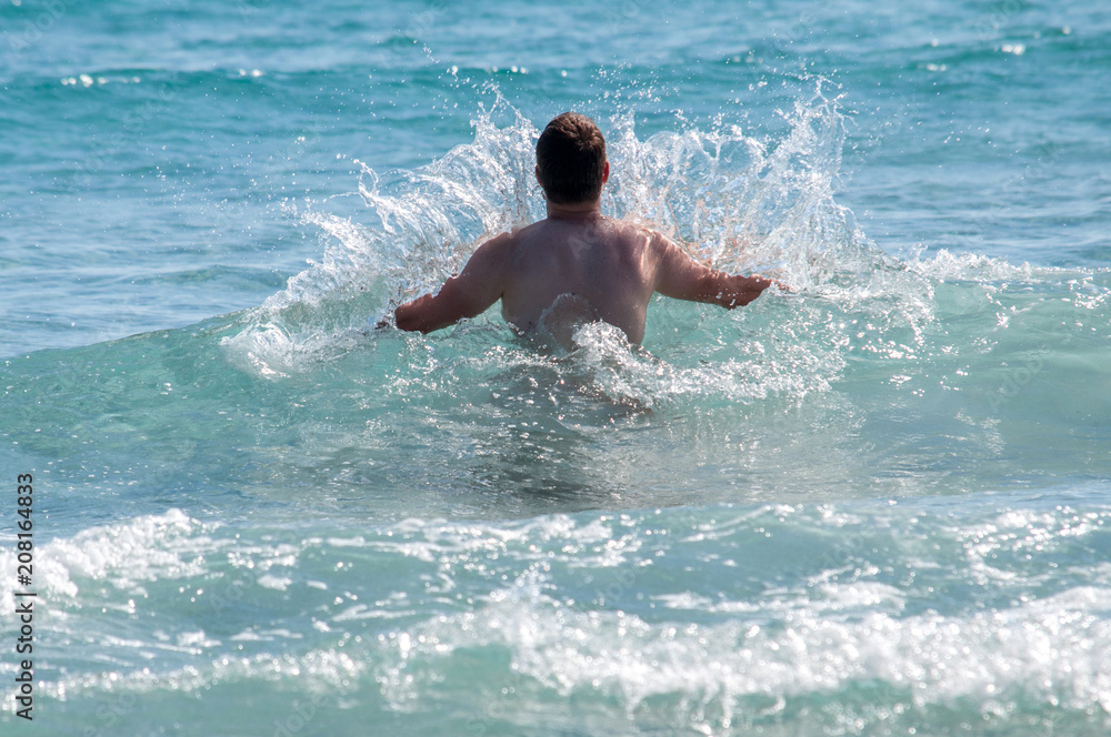 Wall mural young man in waves in the sea