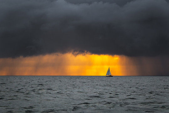 Boat sailing into the storm sunrise