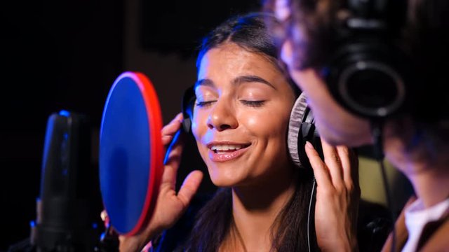 Two young singers performing their song in record studio. Professional musician duet recording new album CD. Beautiful couple working together. Slow motion. 4k