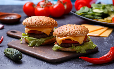 Image of two hamburgers on wooden board, cheese