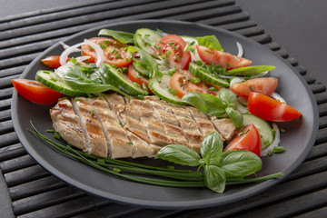 Vegetable salad and grilled chicken on a black background. Healthy food. Diet.