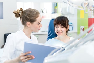 Obraz premium Woman dentist advises the patient in the dental clinic