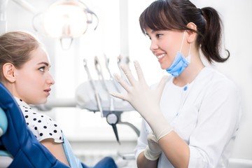 Woman dentist wears gloves preparing to treat the patient's teeth