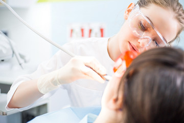 Obraz na płótnie Canvas Girl Dentist With Glasses Treats the Patient's teeth close-up