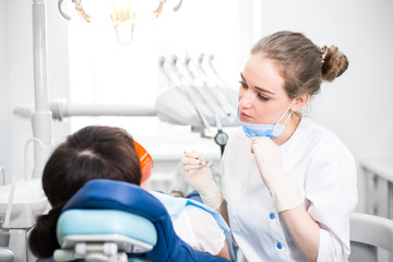 Girl dentist in a mask treats the patient's teeth lying in the dental chair