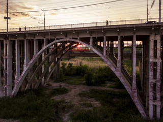 Fototapeta na wymiar silhouette of tram under bridge arch on a sunset