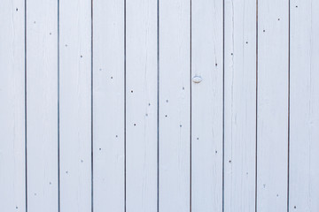 Wooden slats painted white. Wooden door gate white. Boards nailed together. Parallel vertical lines...