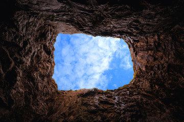 Deep rocky pit, view of the sky from the inside - obrazy, fototapety, plakaty