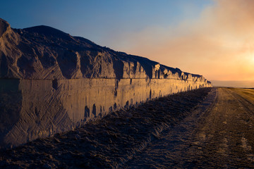 Wall of snow on the roadside after passed plough highlighted by setting sun