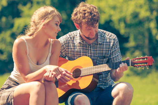 Young couple camping playing guitar outdoor