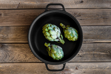 Artichoke in a pan on wooden table