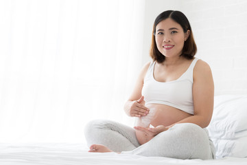 Asian pregnant woman using stretch mark creams