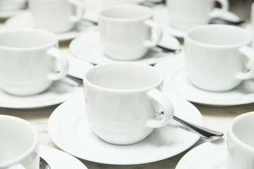 Many rows of white ceramic cup and saucer with teaspoon