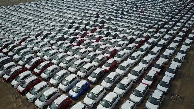 Abstract aerial footage flying over new cars parked on an industrial storage platform in the Port of Singapore