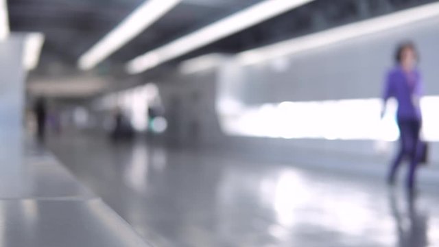 Blurred footage of passengers walking through the walkway corridor to airport terminal. 4K video with defocused effect.