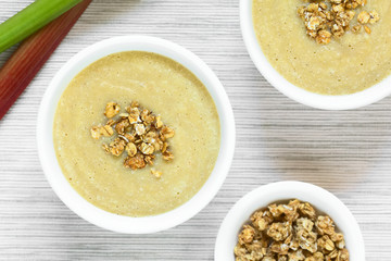 Fresh homemade sweet rhubarb mousse desserts with crunchy granola on top served in bowls, photographed overhead with natural light (Selective Focus, Focus on the top of the desserts)