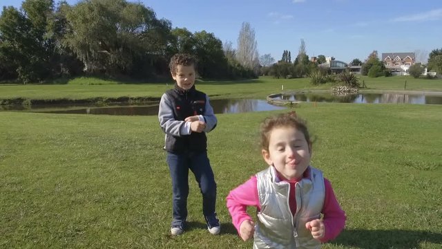 Little Girl & Young Boy Running - Dancing outdoors park – brothers. Slow Motion