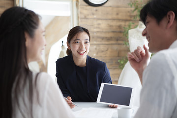 タブレットを片手に結婚式のプランを紹介するプランナー