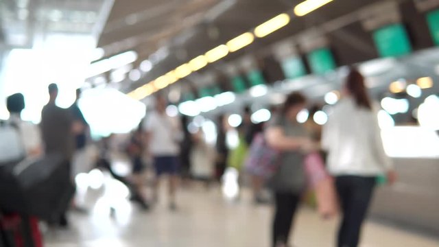 Blurred footage of passengers walking to check-in counter at International airport terminal. 4K video with defocused effect.