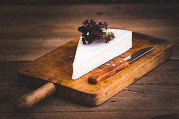 portion of brie cheese camenbert on wood cutting board